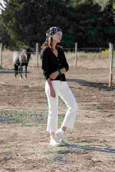 Modèle en jean blanc et bandana fleuri noir et blanc dans un ranch— Lookbook April & C, Occitanie