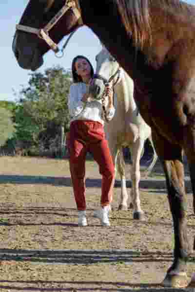 Modèle en blouse blanche et pantalon terracotta entourée de chevaux — Photographe lookbook mode Montpellier, April & C