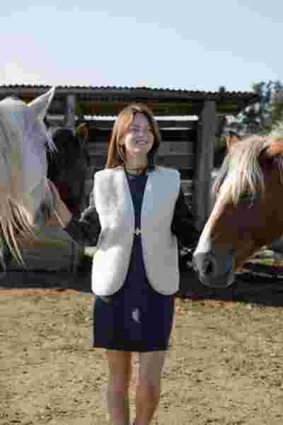 Modèle souriante en robe grise et gilet en laine écru entourée de chevaux — Photographe lookbook mode Montpellier, April & C