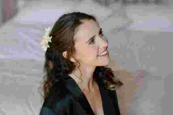 Portrait de la mariée souriante en peignoir noir avec fleur dans les cheveux — Photographe mariage Château Le Bouïs, Gruissan