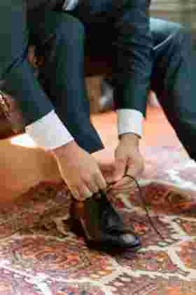 Détail lacets chaussures noires du marié sur tapis oriental — Préparatifs mariage Château Le Bouïs, Occitanie