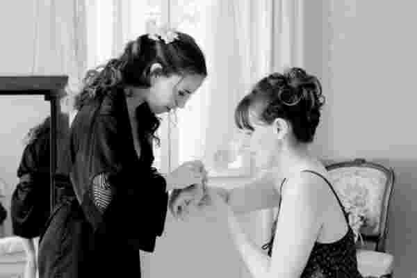 Photo en noir et blanc, mariée aidée par une proche pour s'habiller — Préparatifs mariage Château Le Bouïs, Occitanie