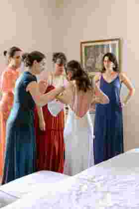 Mariée aidée par ses proches pour enfiler sa robe blanche lors des préparatifs — Château Le Bouïs, Gruissan