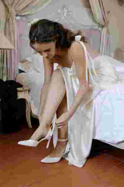 Mariée enfilant ses chaussures blanches à talons dans sa chambre — Préparatifs mariage Gruissan, Occitanie